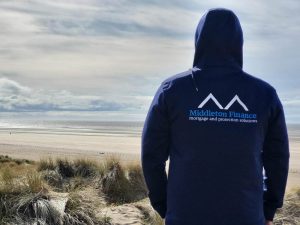 Mortgage advisor wearing a Middleton Finance hoodie, looking out to sea on Southport beach.
